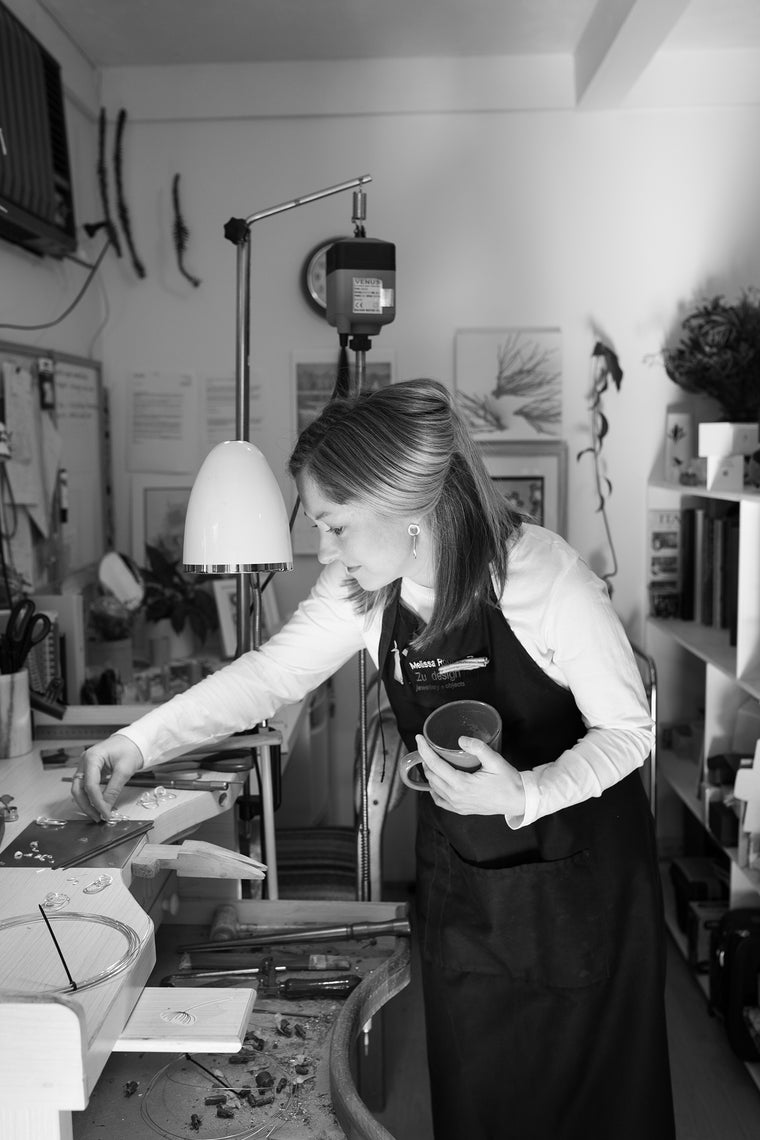 Melissa Gillespie standing at her jewellery bench in her home-studio in Adelaide, South Australia looking at her Sterling Silver Contemporary Jewellery